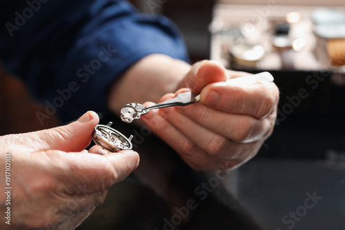 Foto Senior man fixing mechanism of vintage wrist watch at black mirror table indoors
