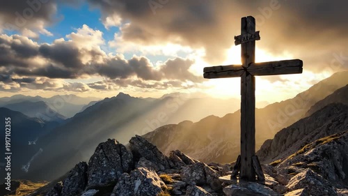 Old wooden cross on rocky mountain peak at golden hour sunset with sun rays through clouds