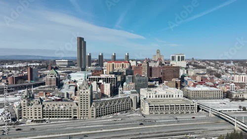 Aerial view of downtown Albany, New York in winter, featuring skyline, historic architecture, and snow-covered streets under clear sky.