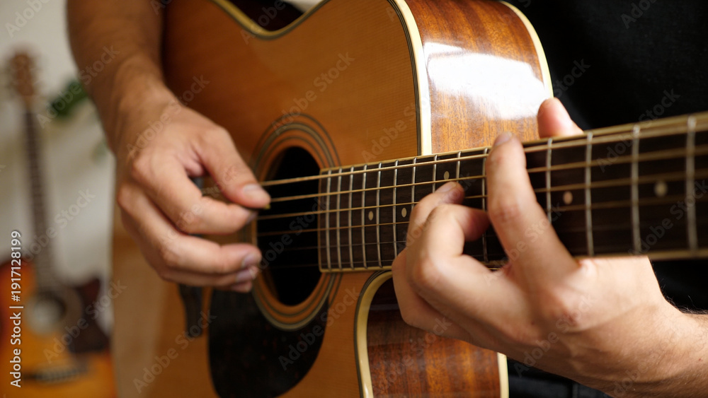 Fototapeta premium Musician playing acoustic guitar with focus on hands and strings. Man practicing musical instrument chords