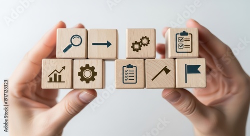 Wooden cubes showing strategic timeline icons arranged by hand using shallow depth and calm white gradient background blur.
