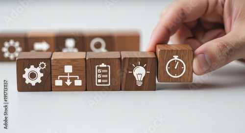 Workflow optimization icons on wooden cubes being positioned carefully with natural focus falloff and white minimal background blur.