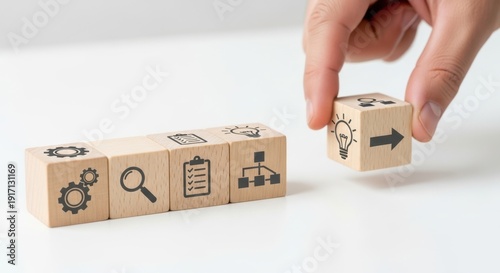 Workflow optimization icons on wooden cubes being positioned carefully with natural focus falloff and white minimal background blur.