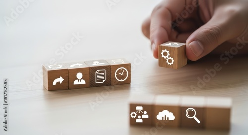 Workflow system icons on wooden cubes placed by hand using natural depth and minimalistic softly blurred surroundings.