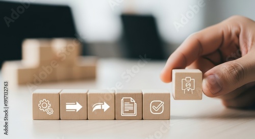 Workflow system icons on wooden cubes placed by hand using natural depth and minimalistic softly blurred surroundings.