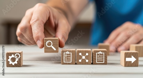 Workflow system icons on wooden cubes placed by hand using natural depth and minimalistic softly blurred surroundings.