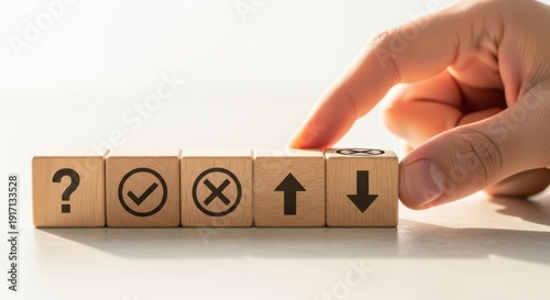 Decision making icons on wooden cubes being aligned by hand using cinematic shallow focus and white background blur effect.
