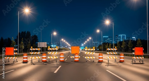Nighttime road closure with orange traffic barrels and barricades on an empty urban highway