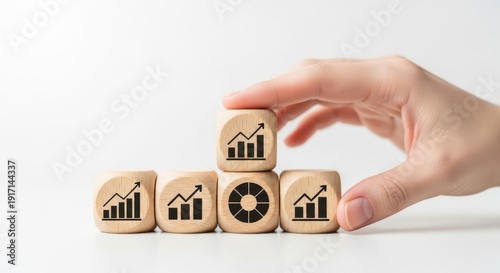 Strategic growth icons on wooden cubes arranged by hand with realistic depth of field and subtle white background blur.