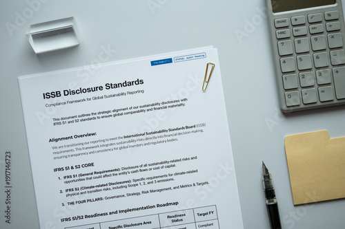 ISSB Disclosure Standards: Realistic mock-up document placed on  with calculator, sticky note, pen.