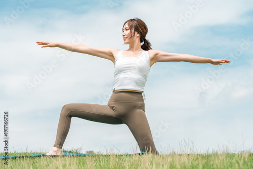 фотографія Young Asian woman doing yoga, pilates and stretching under blue sky