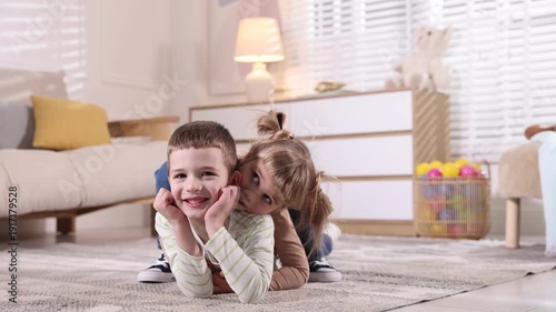 Little brother and sister spending time together on floor indoors