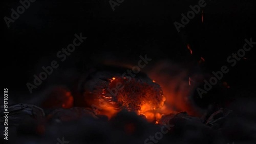Glowing embers and sparks in a dark environment.
