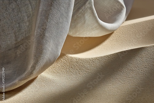 Soft gray fabric draped over sand dune with warm sunlight
