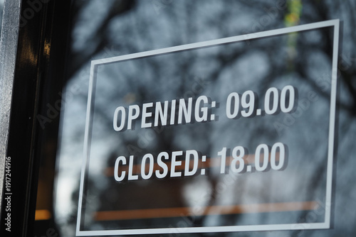 Fotografie Opening hours of a business shown on a glass door