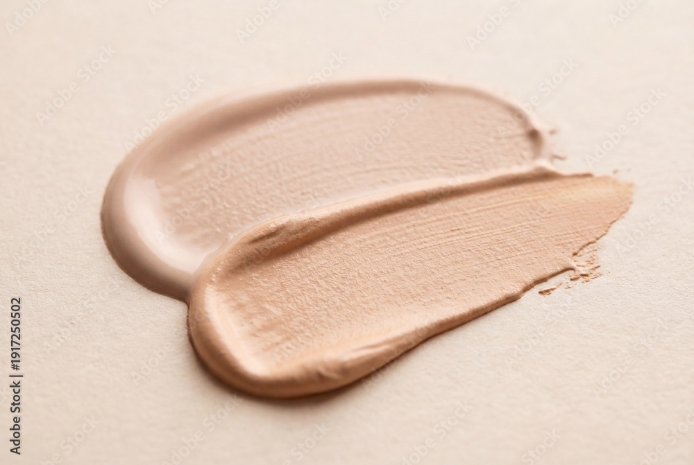 Fototapeta premium Two cosmetic foundation swatches with different tones and textures on a light beige surface