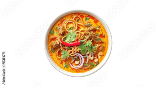 Top view of a bowl of spicy red curry noodle soup with meat, cilantro, and chili on white background.