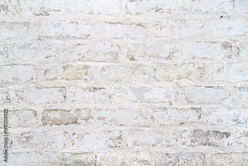 An old peeling white brick wall. Texture of whitewashed brickwork