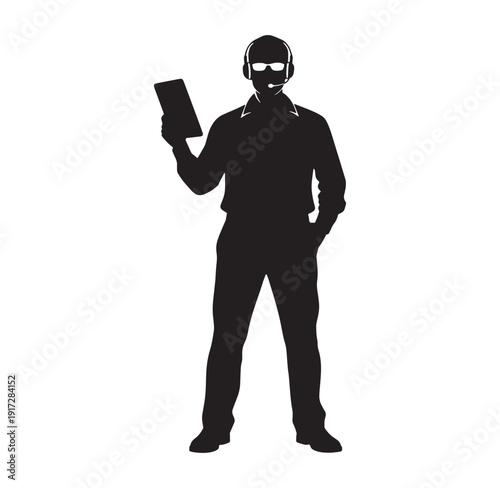 Silhouette of a man wearing headset holding a tablet standing alone