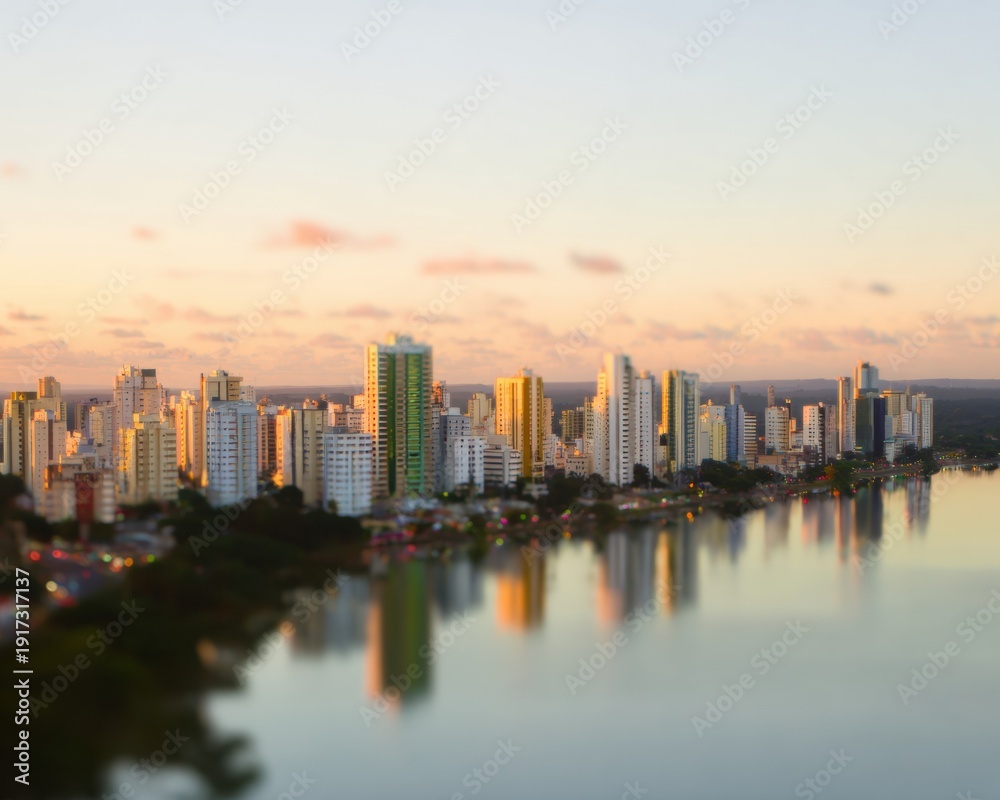 Obraz premium Aerial city skyline reflecting in lake water during sunset with soft pastel tones for urban development presentations and commercial real estate background