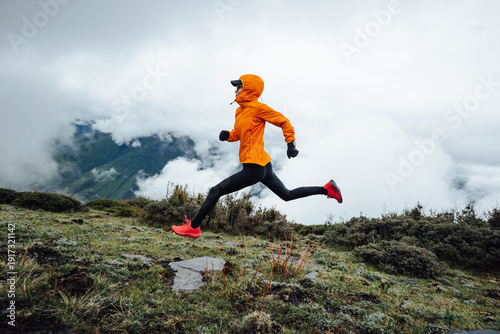 Woman trail runner cross country running at high altitude mountain peak