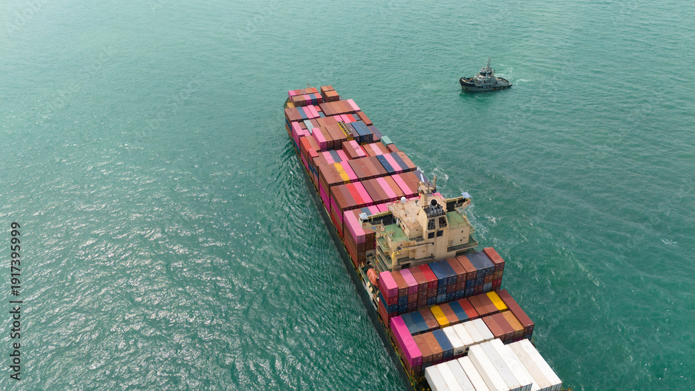 Fototapeta premium Aerial top view over international containers cargo ship at industrial import-export port prepare to load containers with big container loader ship vessel. global transportation and logistic business.