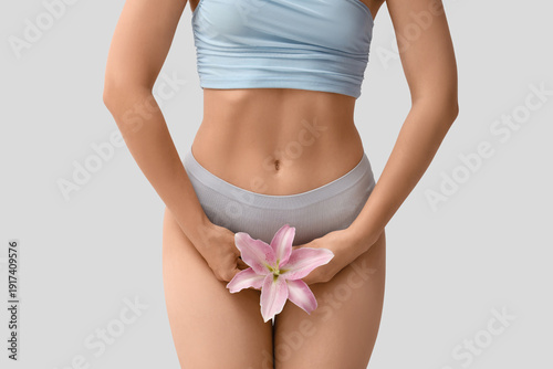Schilderij op canvas Young woman in panties with lily flower on light background
