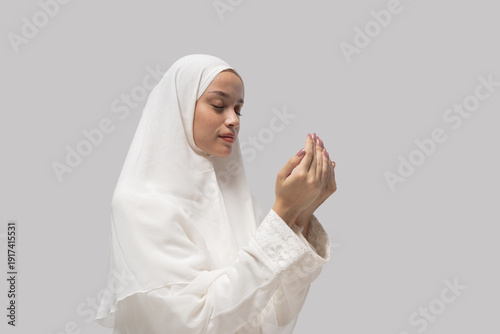 Photos woman in white headscarf gazing at cupped hands with focused expression, conveyi