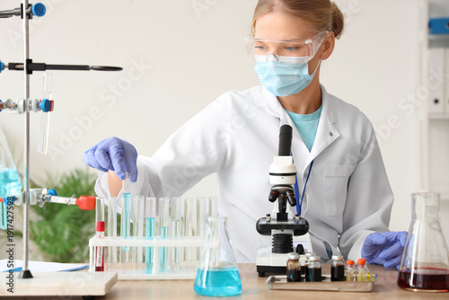 Female scientist with medical mask and test tubes working in laboratory