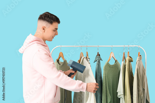 Young man steaming clothes ...