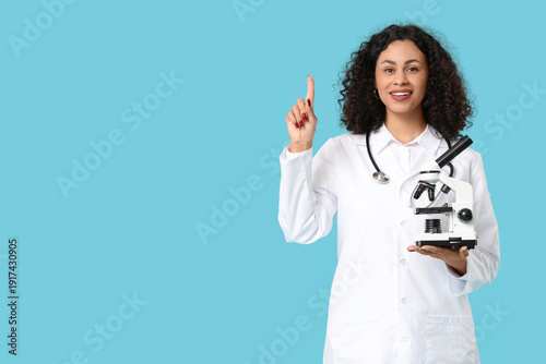 Female African-American scientist with microscope pointing at something on bl...