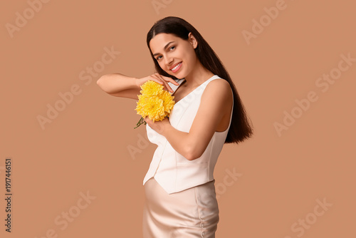 Beautiful young happy woman with bouquet of flowers on beige background