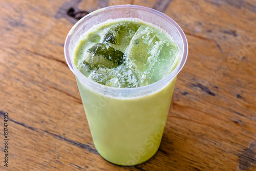 Iced Matcha or Green Tea in Plastic Glass, High Angle View. Wooden table and place for text.table and place for text.