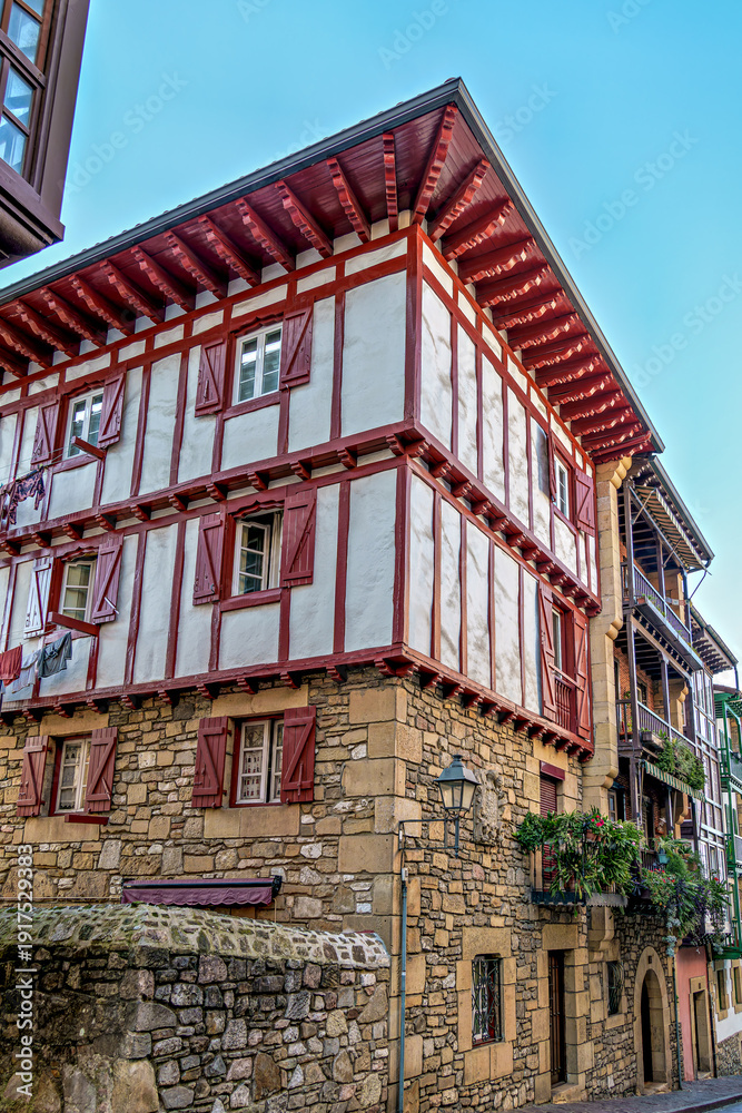 Naklejka premium Colorful Buildings, Red Shutters, Flower Balconies, Cobblestone Street, Traditional Architecture in Hondarribia, Spain