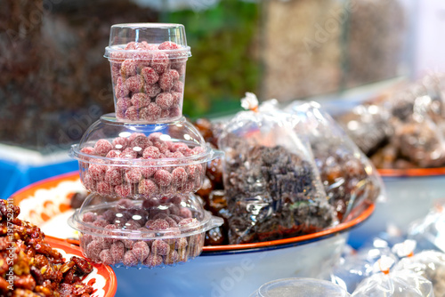 Tamarind candy, Sugar-coated tamarind candy in clear plastic cups stacked at a market stall, vibrant red, sweet and sour, perfect for food and street food themes