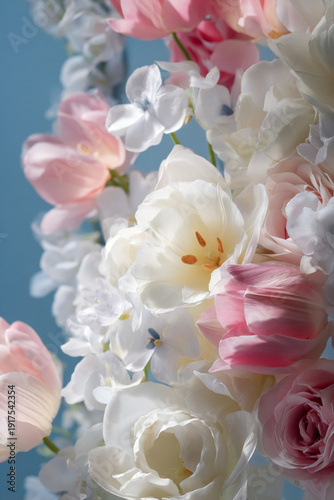 Delicate spring flowers blooming, creating a romantic bouquet of white and pink tulips and roses against a blue background