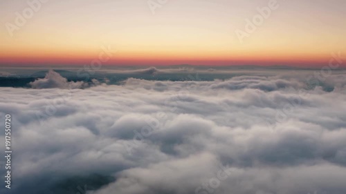 Stunning aerial view of thick white clouds at sunrise with a colorful horizon