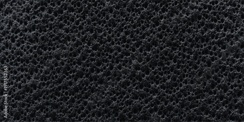 Close-up macro view of a porous dark gray material, like volcanic rock or industrial foam, with a repeating circular hole texture.