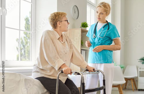 Φωτογραφία Senior patient using walker, nurse standing by to assist and help old woman up and walk in hospital room