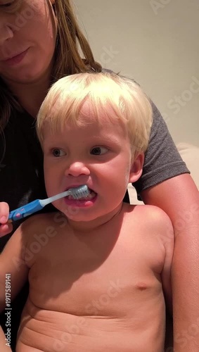 Close-up of a young child brushing his teeth with an adult's help. Oral care, children's hygiene, parental care.
