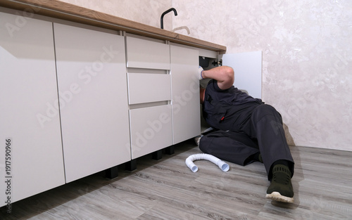 Fotografie Professional plumber fixing a leaking kitchen sink pipe, performing maintenance