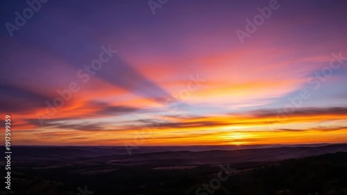 Vibrant sunset paints the sky with fiery colors over the landscape.