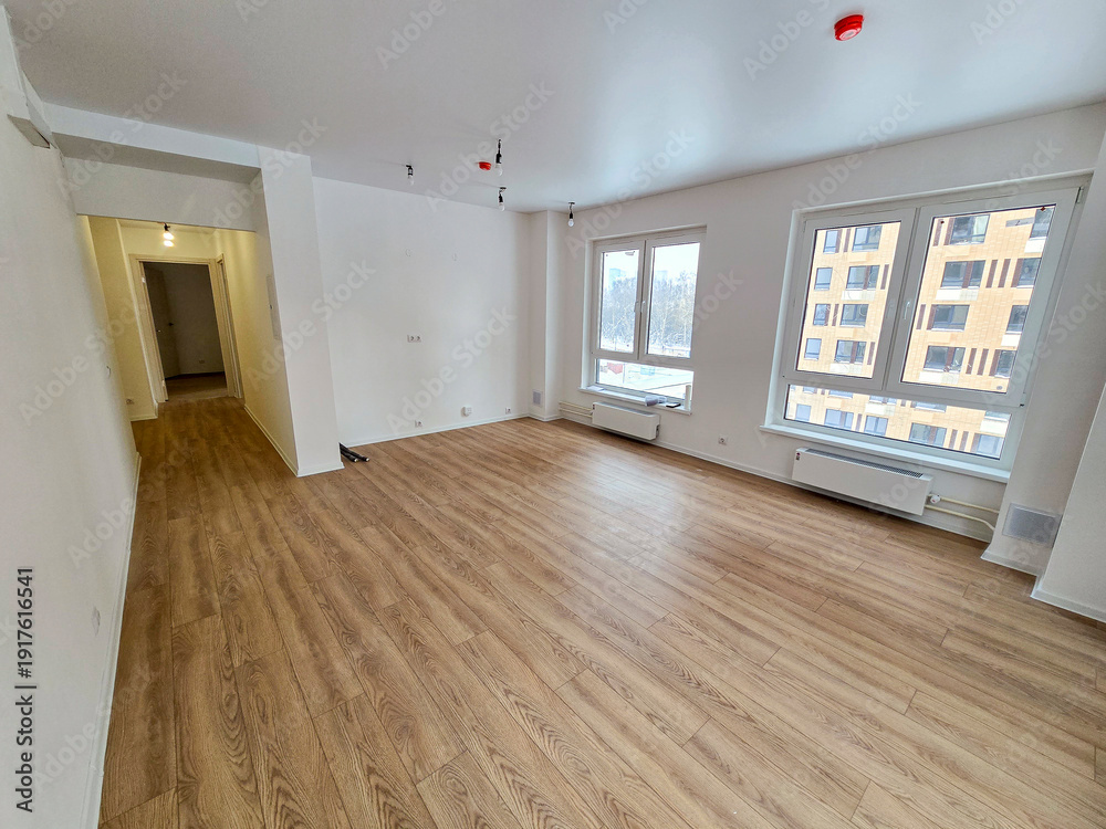 Obraz premium A large empty room with a wooden floor and a white wall. The room is empty and has no furniture
