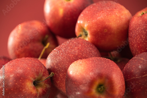 Abundance of fresh picked apples. Fresh Red Apples on red background. A bountiful close-up view of shiny red apples, neatly arranged, emphasizing their fresh and juicy appearance.