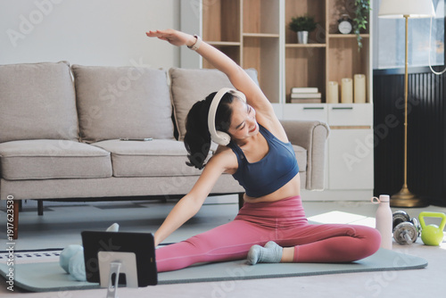 Young Asian sporty attractive people practicing yoga lesson with instructor. Asia group of women exercising healthy lifestyle in fitness studio. Sport activity, gymnastics or ballet dancing class.