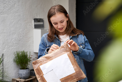 Girl standing in front of house, happy to receive a parcel
