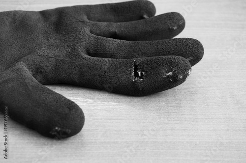 Monochrome image, black rubber working gloves with a hole, space for text.