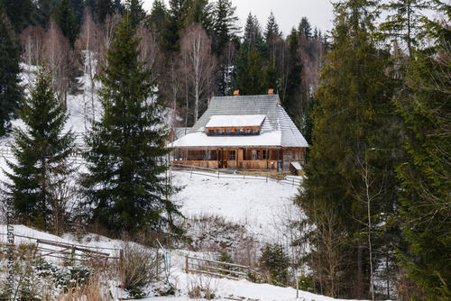 Snowy wooden cabin in forest landscape