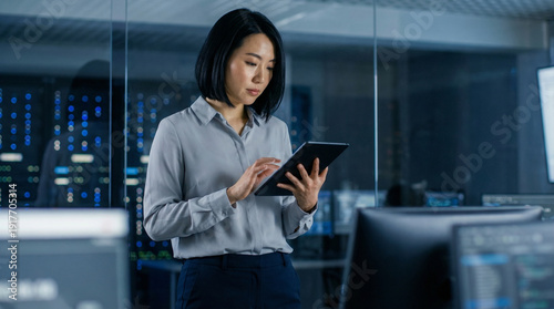 Female IT Specialist or Data Scientist Using Tablet in High-Tech Server Room, Asian Professional Woman Monitoring System Security in Modern Data Center, Cloud Computing Concept