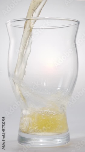 Pouring beer into a glass on a white background. Gas bubbles rise, forming foam.